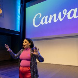 Engaging presentation by a woman in a modern auditorium setting with Canva branding.